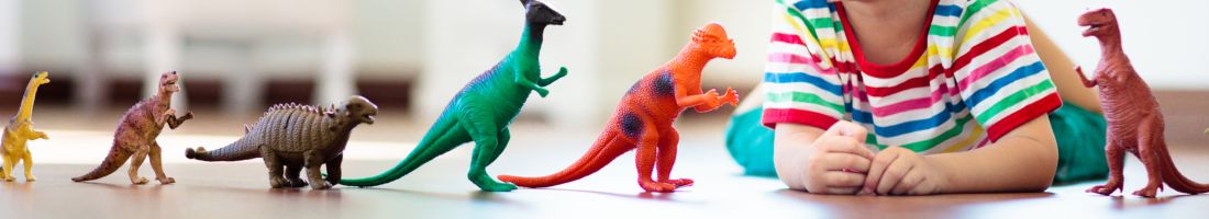 Child playing with toy dinosaurs. Kids toys.