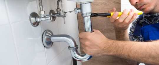 Plumber fixing sink pipes in a bathroom